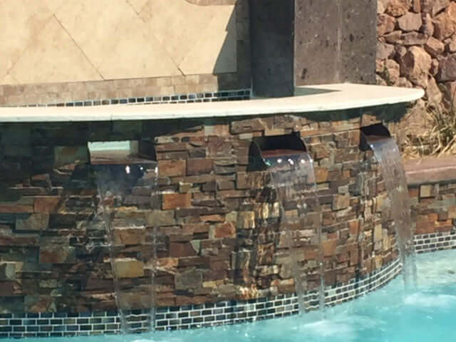 Copper brown patina water spillway installed in spa to pool water spillway