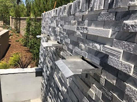Brushed Stainless Steel Waterfall Spillway Fountain Scupper on Gray Stacked Stone
