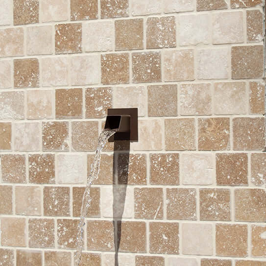 Square water spout mask displayed in fountain wall outdoor